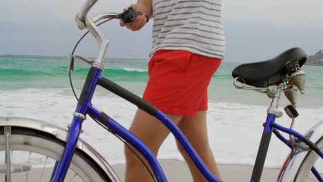 side view of caucasian man walking with bicycle on the beach 4k