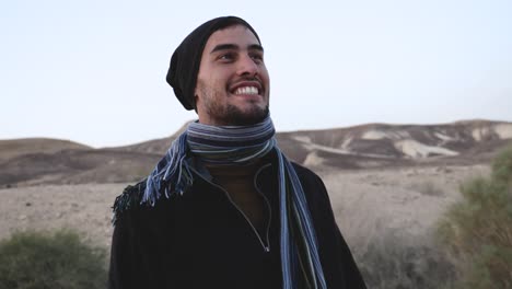 portrait orbiting shot of young excited traveler looking around enjoying the view of endless negev desert, israel at sunset in slow motion