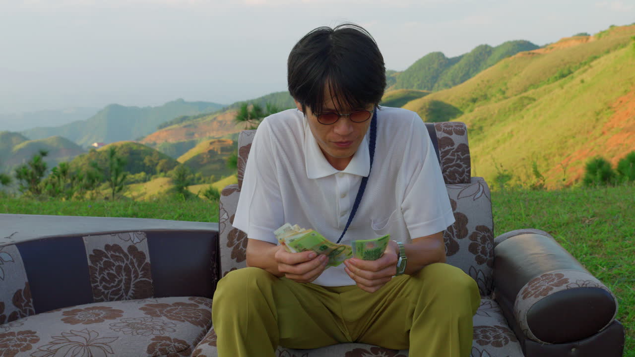 business man sitting in nature on a vintage couch counting paper bills money for financial freedom stream income