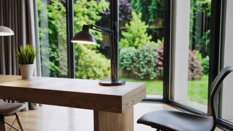modern desk with lamp and plant in a room overlooking a garden