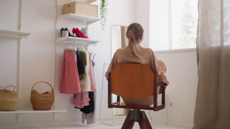 satisfied woman spins on chair after choosing perfect outfit