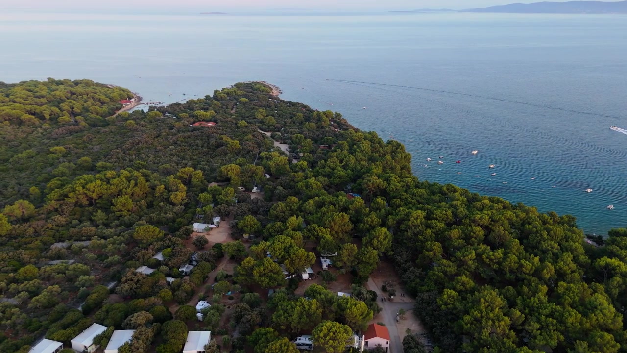 Campeggio FKK Naturista Baldarin a Punta Kriza sull'isola di Cherso, Croazia, ripresa aerea con drone in una splendida serata estiva. Camper, autocaravan, natura costiera, mare Adriatico cristallino, baie panoramiche.