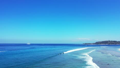 peaceful seascape with endless blue ocean and shallow turquoise lagoon with white waves foaming over coral reefs under bright sky in malaysia