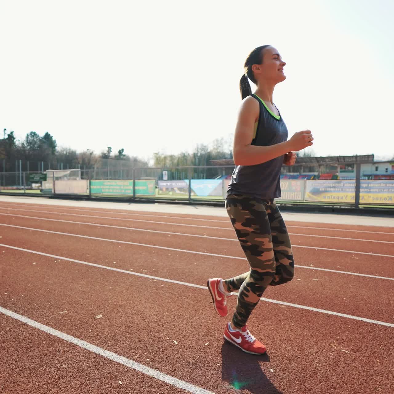 Young athletic woman running on stadium track. Beautiful body. Healthy fitness lifestyle