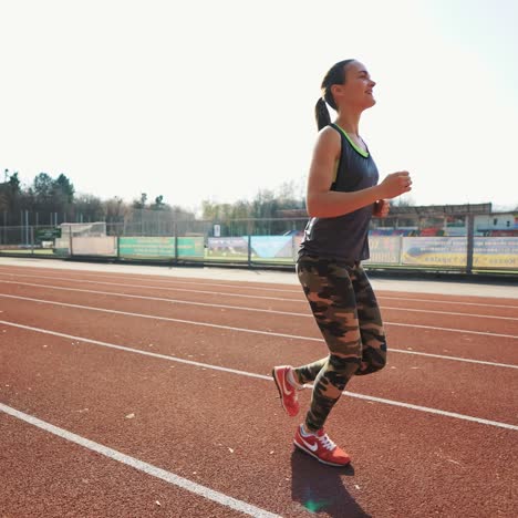 young athletic woman running on stadium track. beautiful body. healthy fitness lifestyle