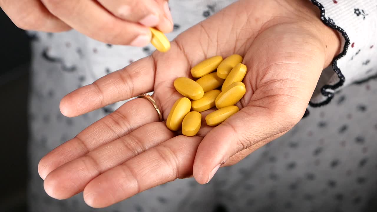 Hand holding yellow pills