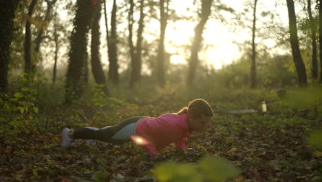 woman exercising push-ups in park at sunrise