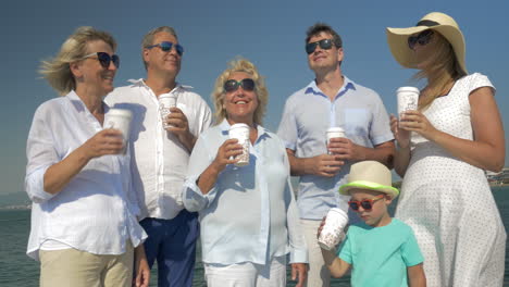 big family drinking sea from paper cups by the sea