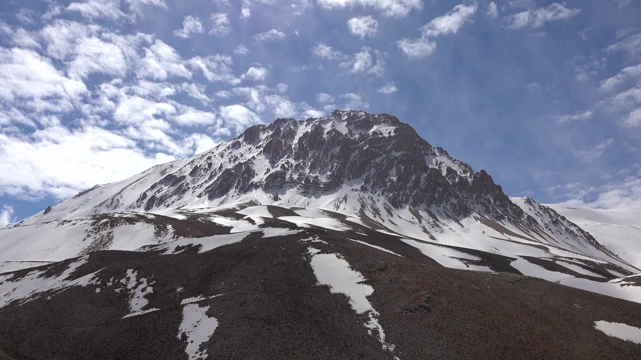 Cima di montagna innevata sotto un cielo blu con nuvole
