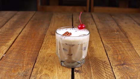 waiter delivering a kahlua based drink with coffee, alcohol and milk on a wooden table