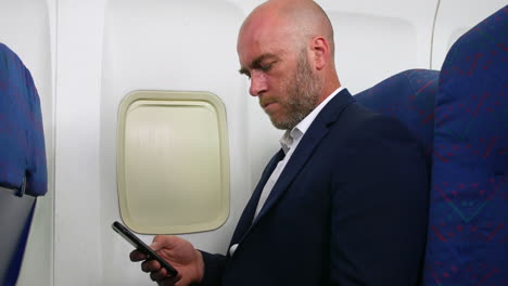 Un-Hombre-Revisando-Mensajes-En-Su-Teléfono-Celular-En-Un-Avión