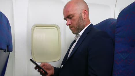 a man checking messages on his cell phone on a plane