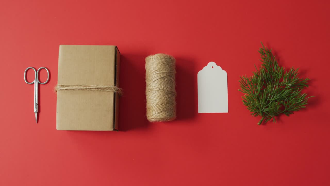 tijeras, caja, cuerda y rama de abeto sobre fondo rojo