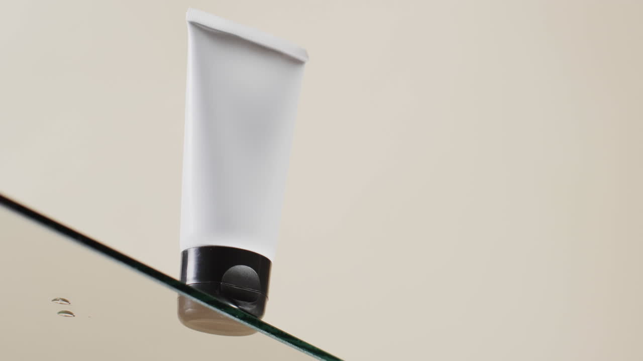 video vertical de un tubo de producto de belleza en un estante de vidrio con espacio de copia en un fondo blanco