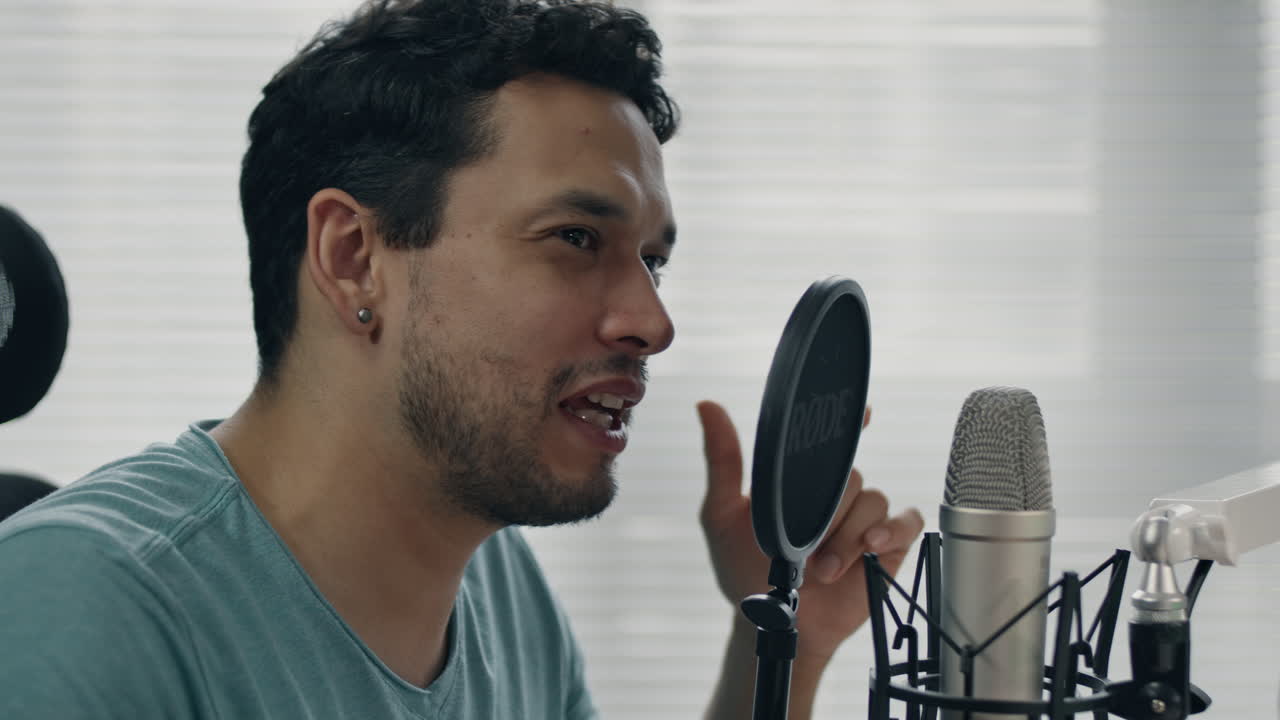 Primo piano di una persona che parla al microfono in un ambiente creativo.