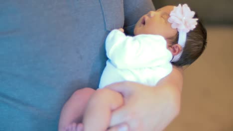 un padre sacude a su bebé recién nacido dormido en sus brazos