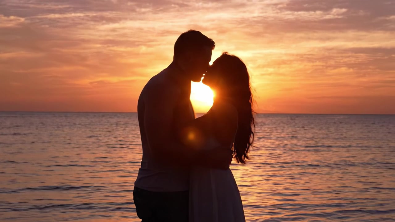 Silhuetas Românticas ao Pôr do Sol: Um Casal se Abraçando na Praia Enquanto o Sol se Põe Sobre o Oceano, Capturando um Momento Íntimo em um Lindo Cenário Natural