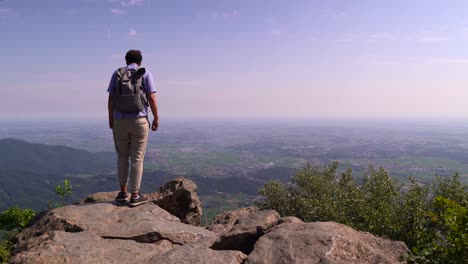 excursionista con mochila de pie en el borde del acantilado en la cima de la montaña en un día soleado en japón