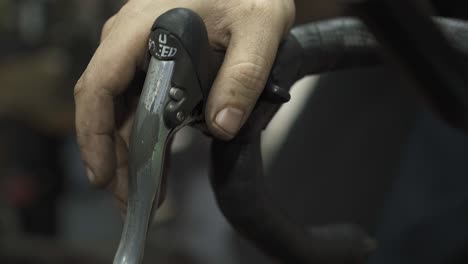 A-bicycle-mechanic-testing-the-rear-derailleur-of-a-road-bike-with-hands-in-the-foreground