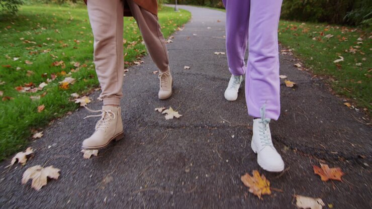 Deux femmes marchent sur le chemin dans le parc en automne, côte à côte, seules les jambes sont visibles dans le cadre