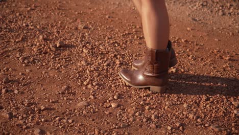 woman with brown boots walking on a dirt road