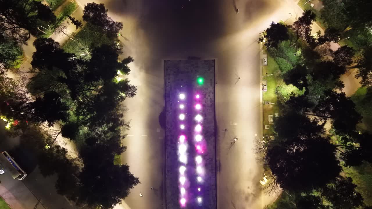 Panorama noturno de drone de uma fonte em praça pública com iluminação dinâmica, CDMX