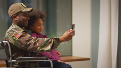 Soldado-Americano-Herido-Vistiendo-Uniforme-En-Silla-De-Ruedas-Posando-Para-Selfie-Por-Teléfono-Con-Su-Hija