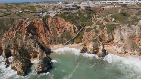 Holztreppen-Führen-Hinunter-Zum-Sandstrand-Von-Ponta-Da-Piedade,-Drohne-Zieht-Sich-Zurück-Und-Erhebt-Sich