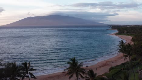 low panning aerial shot of the pristine beaches of wailea with west maui in the distance at sunset in hawai'i