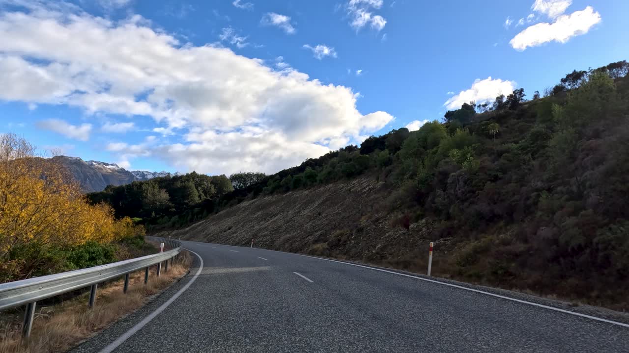 Conducción en carretera de montaña sinuosa con follaje otoñal, vistas al lago, luz natural y cámara estable