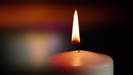 the showcases of colorful single candlelight on black background with the effect of light and slow motion