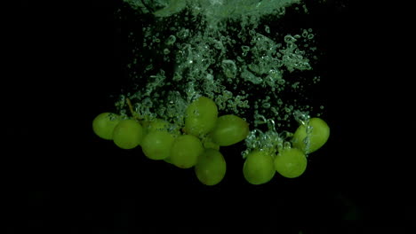 uvas que caen en el agua sobre un fondo negro