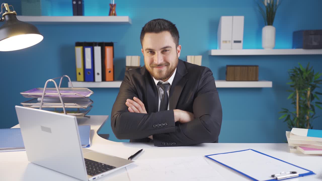el hombre de negocios se alegra de lo que ve en la computadora portátil y mira a la cámara con una sonrisa.
