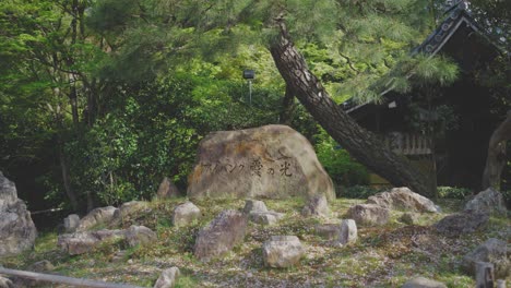 calming garden view in kyoto featuring a stone with japanese inscription amid lush greenery. perfect for themes of nature, culture, and tranquility.