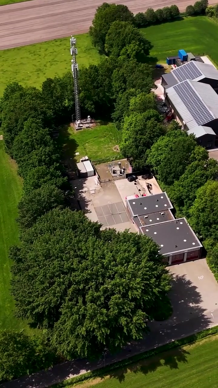 Aerial View of Communication Tower and Buildings with Solar Panels in Rural Landscape