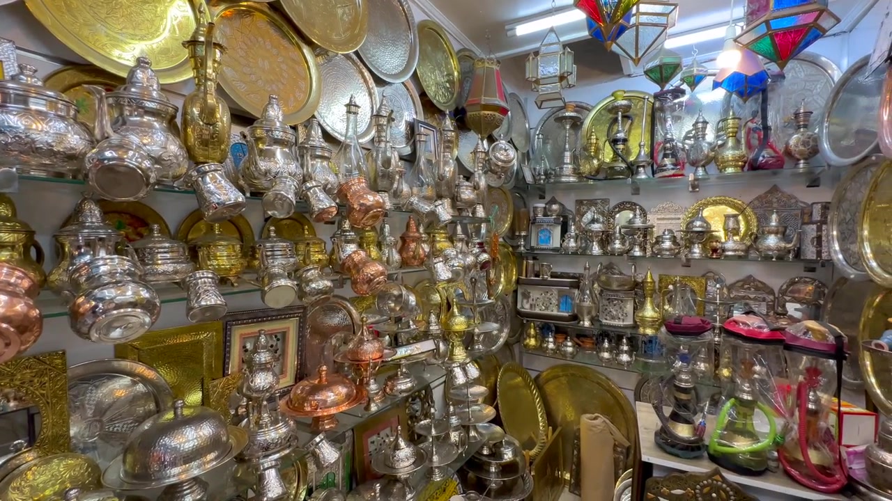 Hareketli bir Tunus pazar tezgahında raflar pirinç tepsiler, gümüş çaydanlıklar ve süslü metal eşyalarla dolup taşıyor. Tunus.