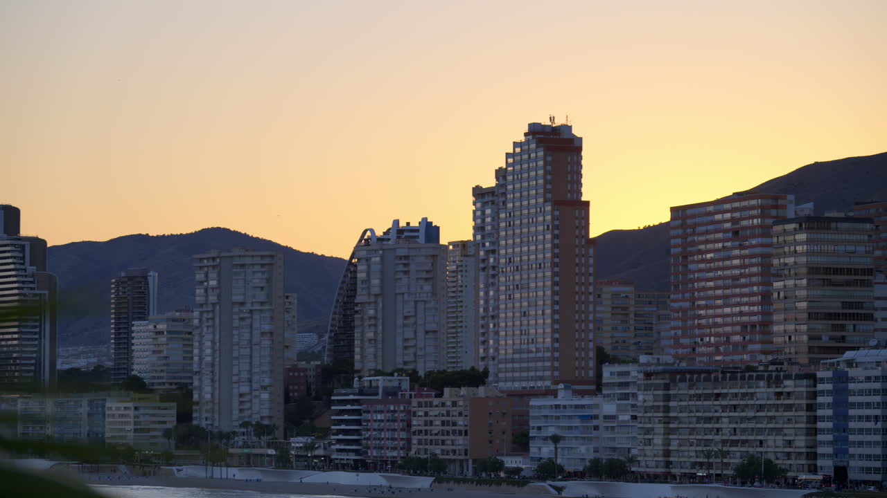 Horizonte litorâneo moderno na hora azul, torres com silhuetas contra montanhas suaves em Alicante, Espanha
