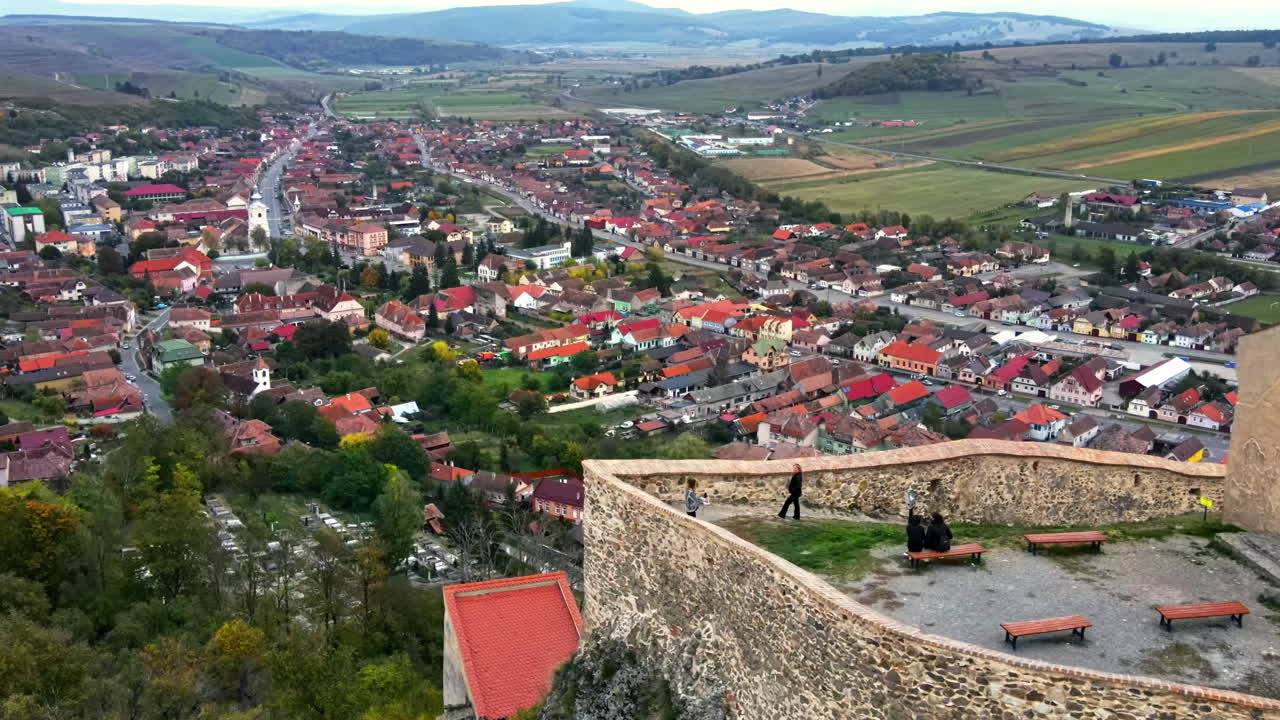 Aerial drone view of Rupea Fortress, Romania. Citadel located on a cliff, tourists, town