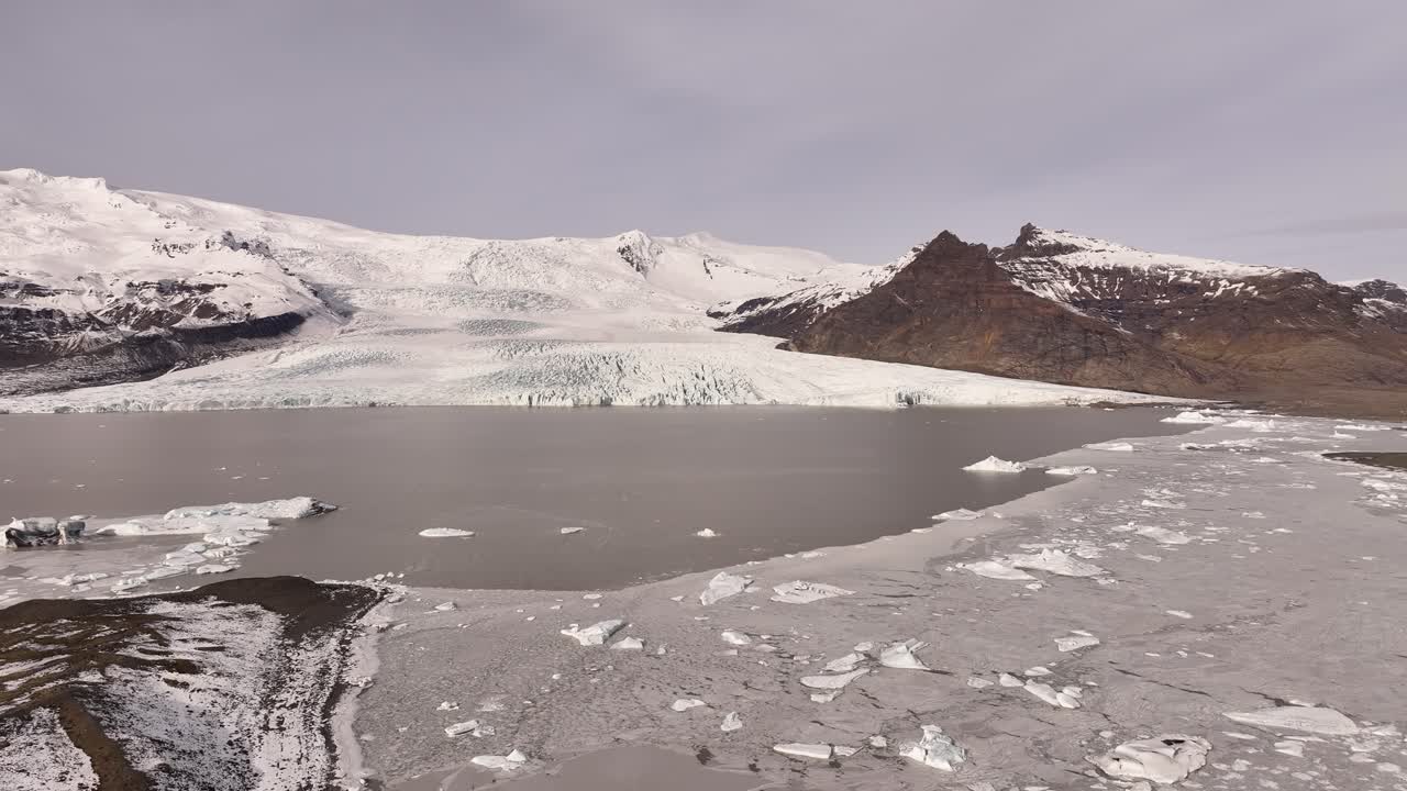 Frozen Fjallsárlón lagoon with scattered ice near Vatnajökull glacier in Iceland