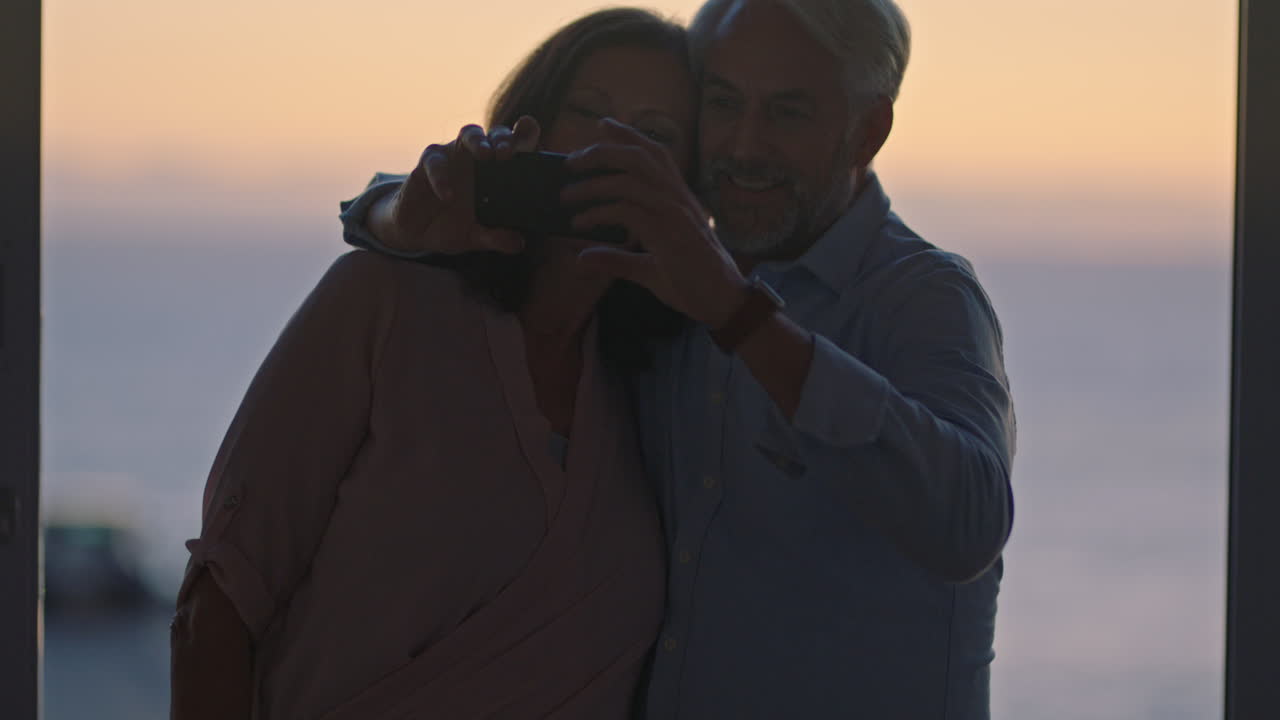 happy old couple taking photo using smartphone hugging enjoying successful retirement sharing vacation on social media at sunset