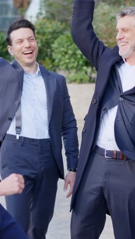 smiling businessmen clapping outdoors