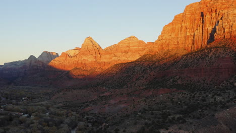 orange sunlight falling on vertical rocky canyons of springdale, zion national park