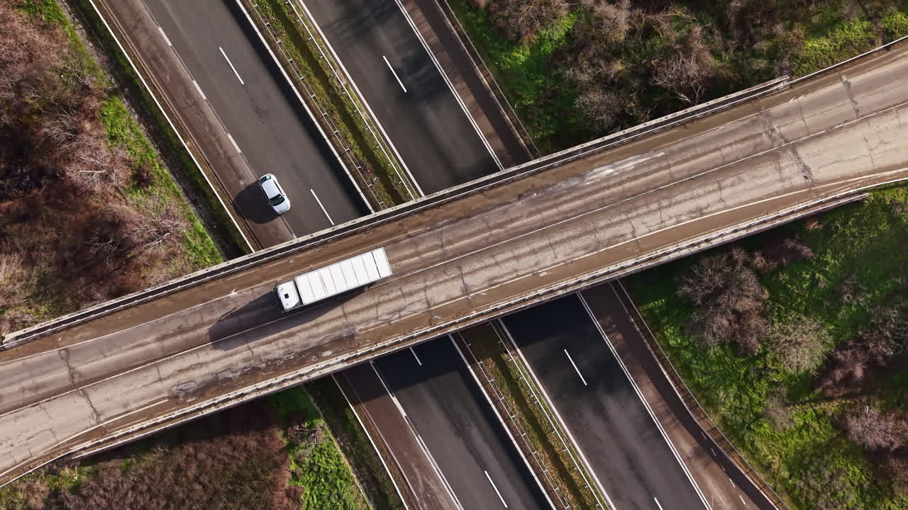 Vista de varias carreteras que se cruzan en una ciudad rodeada de árboles verdes durante el día, mostrando vehículos circulando en varias direcciones