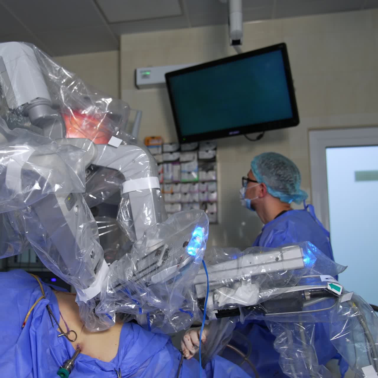 The patient is operated by the futuristic robotic equipment. Male doctor watches the operation carefully at the screen