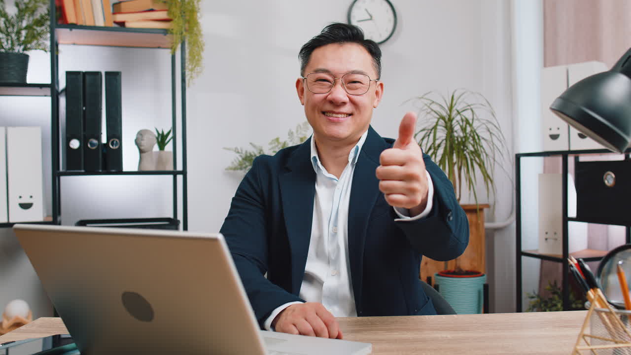 Happy business man looking approvingly at camera showing thumbs up like positive sign good news