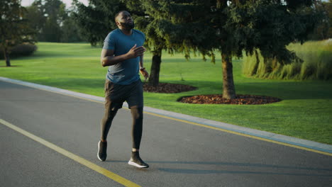 african american runner jogging in park. sportsman doing cardio workout outdoors