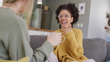 happy diverse teenager girls friends drinking coffee and talking at home, slow motion