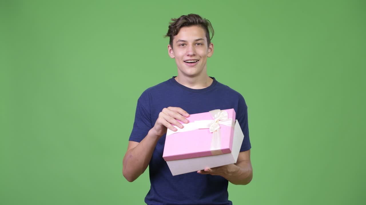 Young handsome teenage boy opening gift box