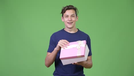 young handsome teenage boy opening gift box