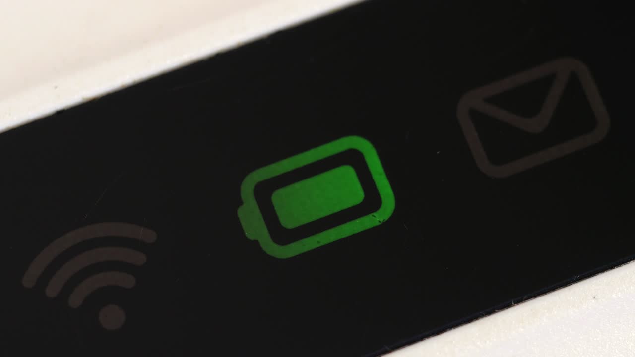Primo piano estremo dell'icona verde lampeggiante della batteria accanto ai simboli spenti di Wi-Fi e posta.